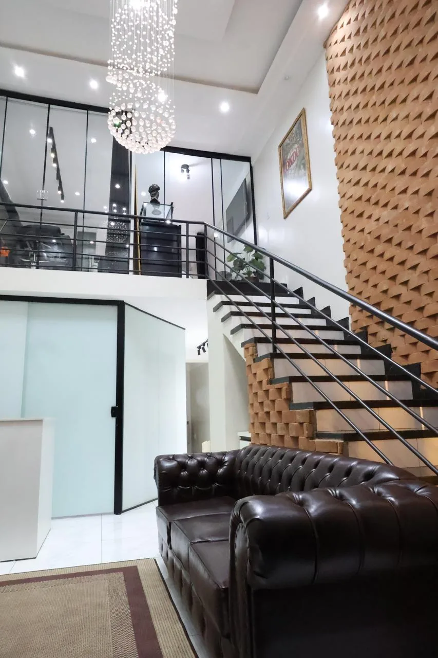 Pé-direito duplo com sofá chesterfield, escadaria e lustre de cristal