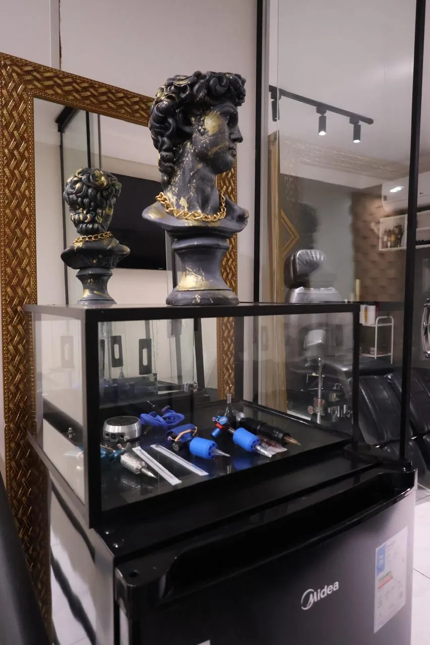 Vitrine com máquinas de tatuagem e bustos clássicos